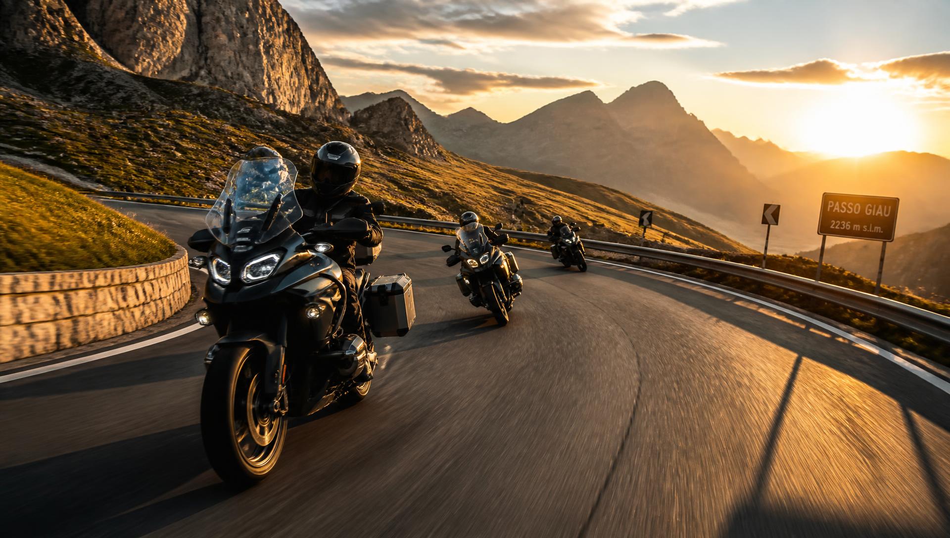 Gruppo di motociclisti in curva su un passo alpino al tramonto
